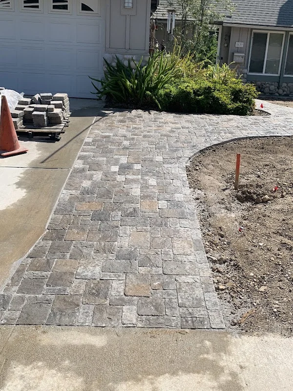 Gray and tan permeable concrete pavers installed in geometric pattern on residential driveway