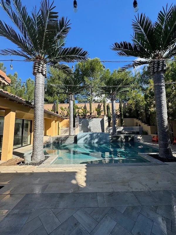 Palm trees flanking pool with herringbone paver deck and pergola structure
