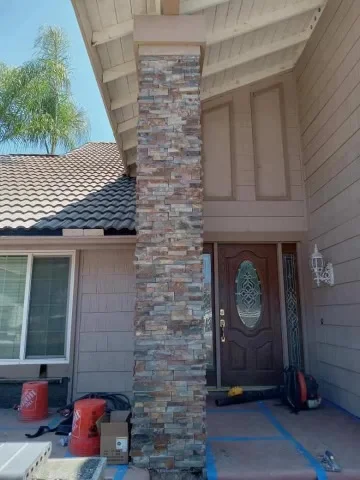 Stacked stone veneer chimney with mixed-color brick on residential home exterior