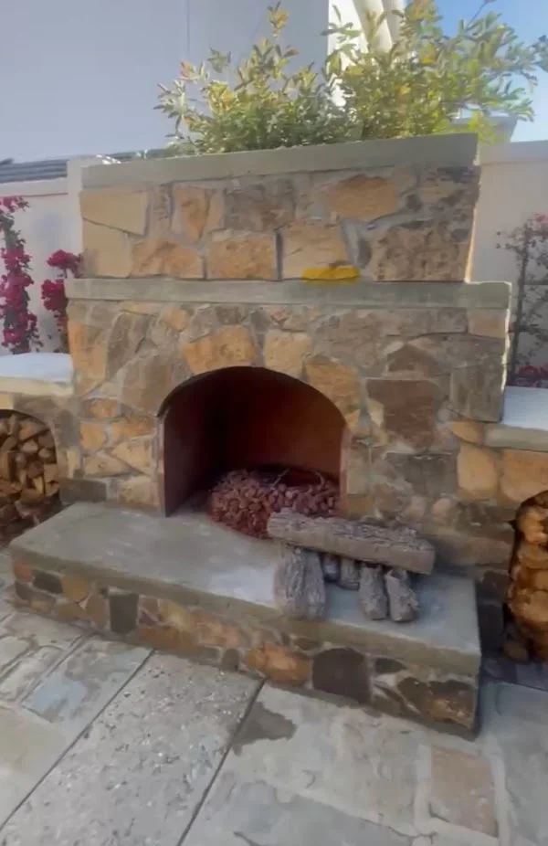 Stacked stone outdoor fireplace with arched opening and concrete hearth