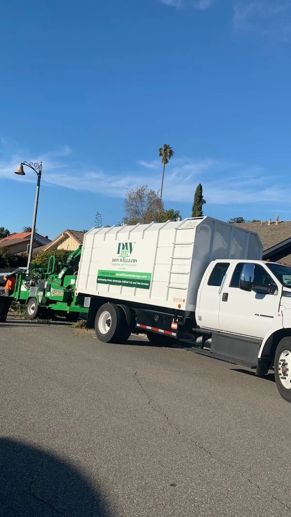 White landscape service truck with debris box and green chipper equipment