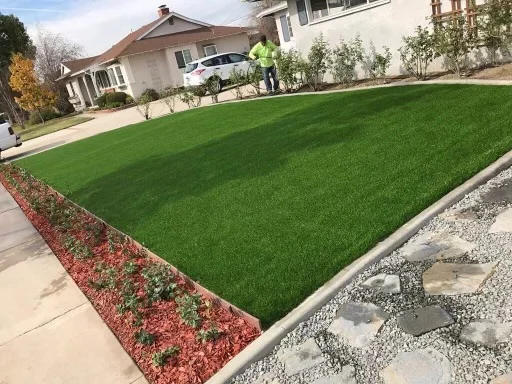 Newly installed sod lawn with red mulch planting beds, concrete walkway, and landscape edging