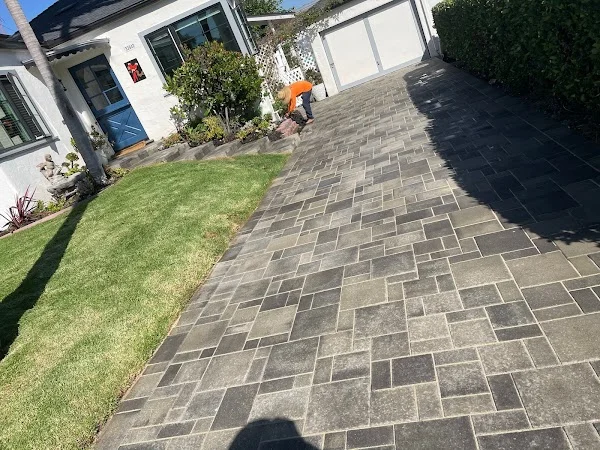 Charcoal and gray paver patio with herringbone pattern layout next to manicured lawn