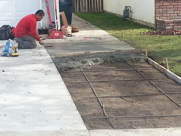 Concrete driveway extension with reinforcement mesh and worker finishing new section