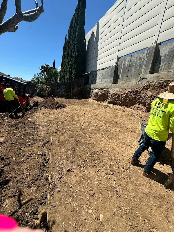 Excavated and graded dirt site with survey line, construction crew in safety vests