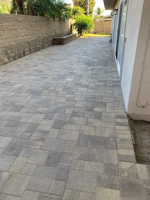 Gray concrete paver patio in herringbone pattern with retaining wall and landscaping